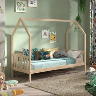 Lit cabane pour enfant en bois naturel avec barrières latérales, décoré de coussins colorés et situé dans une chambre chaleureuse aux murs verts pastel.