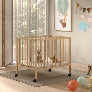 Parc bébé carré en bois naturel avec barreaux verticaux et roulettes, installé dans une chambre lumineuse décorée de jouets, de peluches et d'illustrations murales enfantines.