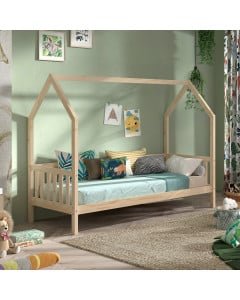 Lit cabane pour enfant en bois naturel avec barrières latérales, décoré de coussins colorés et situé dans une chambre chaleureuse aux murs verts pastel.