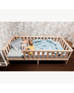 Alt text : Lit à faible hauteur ceinturé de barrières sécurisées Cocon 80x160 en bois massif, blanc et bois naturel, fabriqué en Lettonie par Mandrel. Sommier inclus, idéal pour un matelas 80x160.
