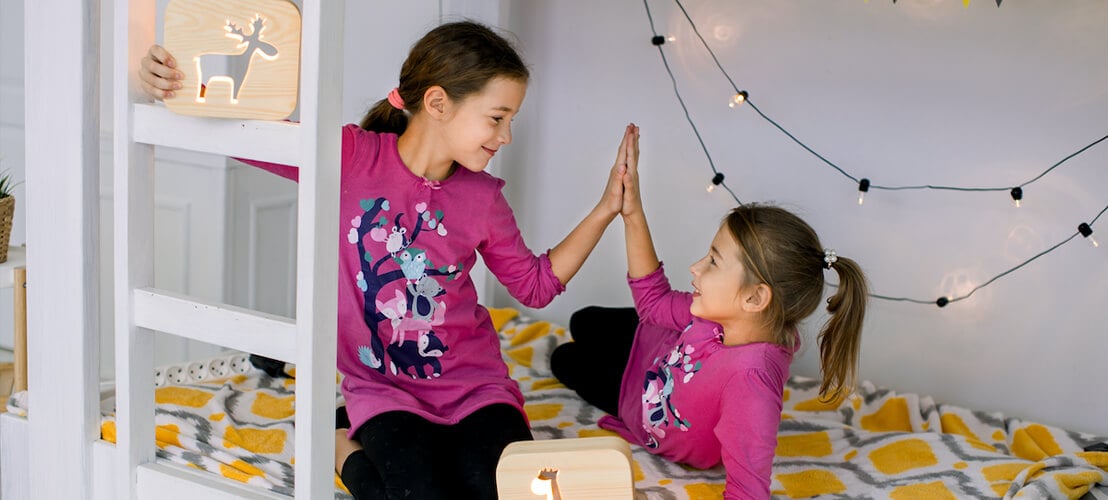 Photo deux mignonnes sœurs de 10 ans en pyjama lumineux s'amusant, jouant et s'amusant dans un lit superposé