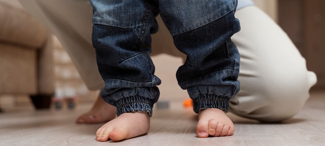 Image d’un jeune enfant qui marche pieds nus sur un sol en parquet