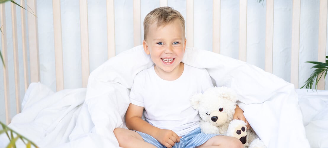 Photo d’un petit garçon souriant dans son lit