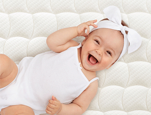 Bébé souriant allongé sur un matelas bébé acheter chez le Jurassien